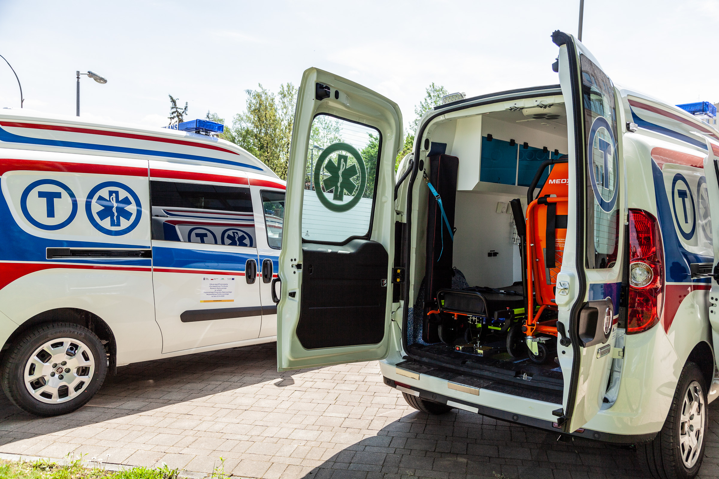Na zdjęciu ambulans z otwartymi tylnymi drzwiami, z widocznym w środku wyposażeniem 