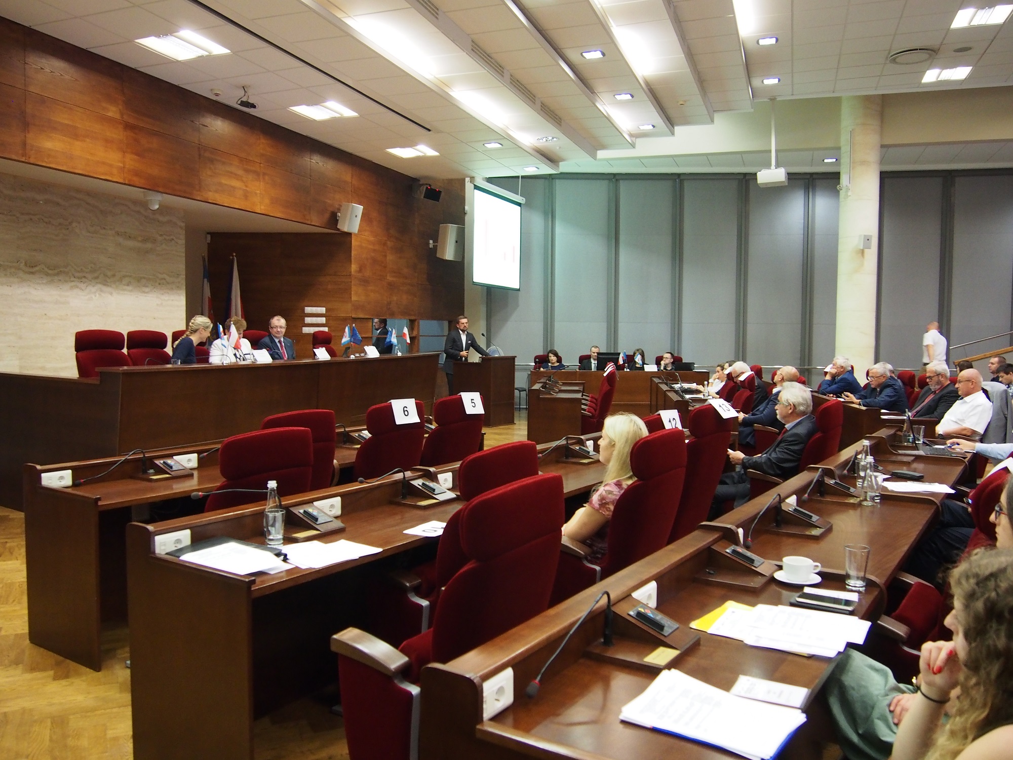 Zdjęcie przedstawia stół prezydialny podczas obrad XVII posiedzenia Komitetu Monitorującego oraz pozostałych uczestników spotkania. 